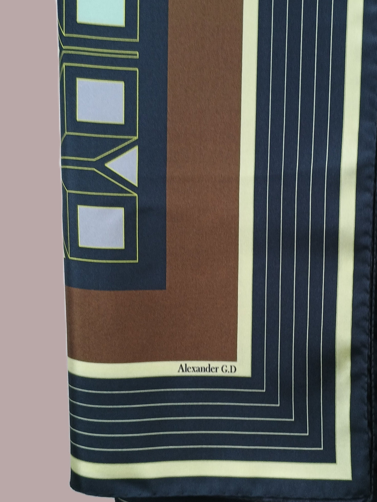 Silkscarf Granada stripes drapes softly over a model's shoulder, revealing the high level of craftsmanship in the silk print machine/hand roll hemming