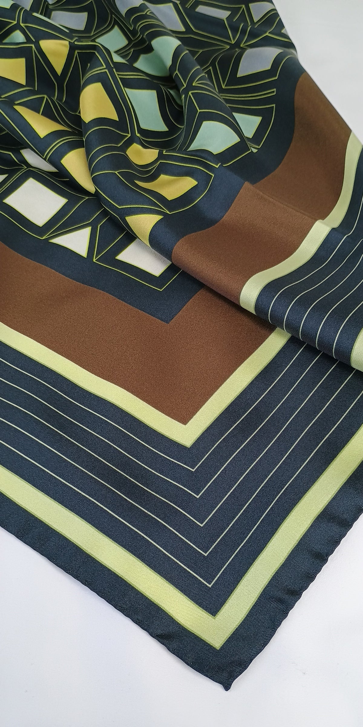 Patterned silk scarf with geometric design on a dark grey brown yellow on white background 90 x 90 cm showing hemming