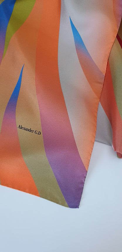 Colorful scarf with wavy pattern on a white background, featuring the brand 'Alexander G.D'.